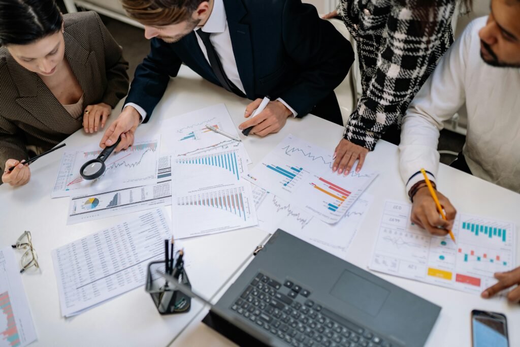 A group of professionals reviewing financial charts in an office meeting setting.