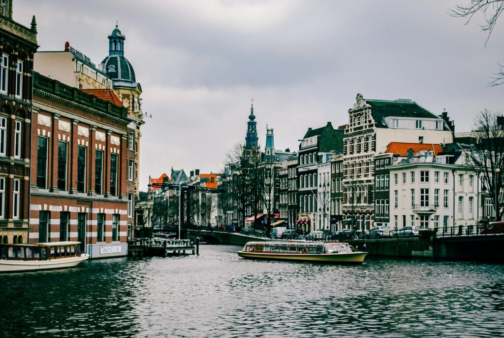 Charming canal scene in Amsterdam with historic architecture and a passing boat.